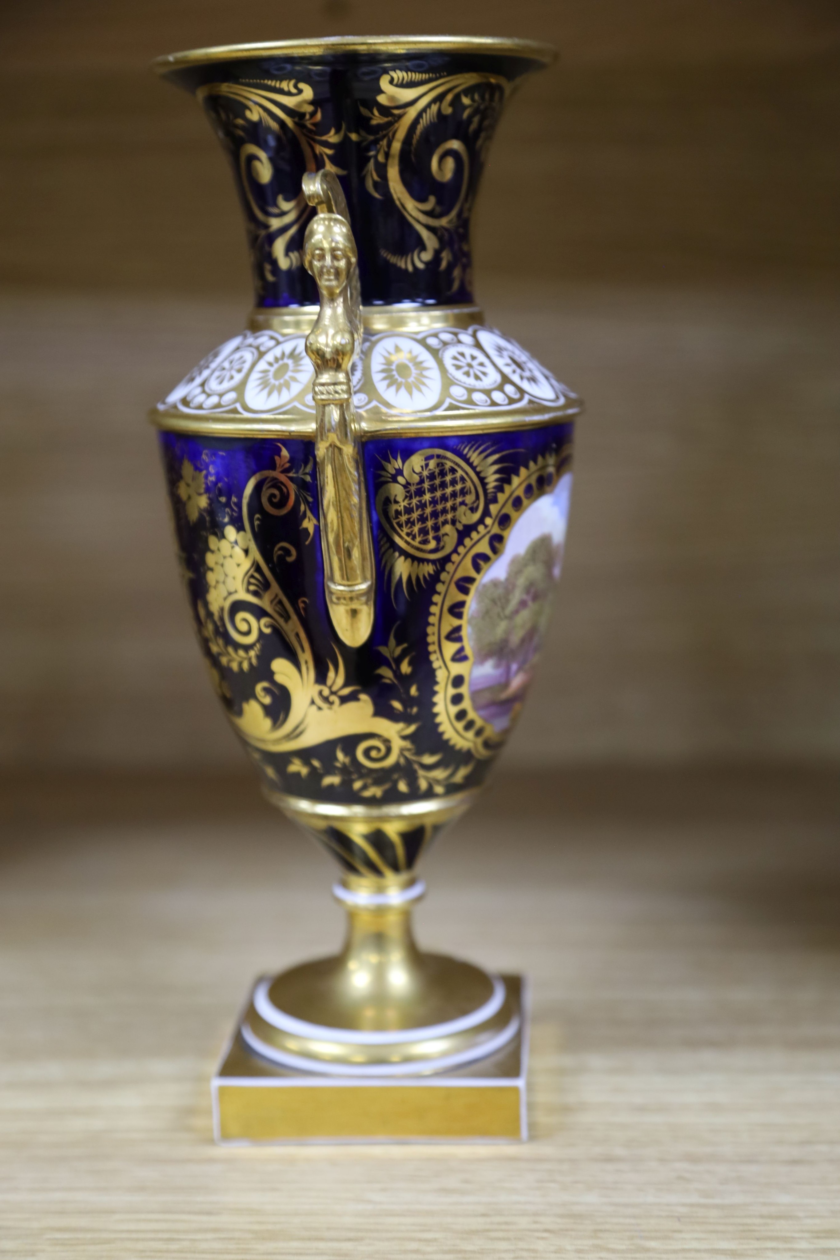 A garniture of three early 19th century English porcelain vases, c.1815-20, each painted with topographical views, tallest 26cm